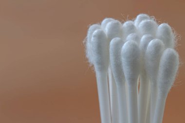 Plastik malzemeli beyaz pamuk tomurcukları, kahverengi arka planda izole edilmiş, sağlık, güzellik ve hijyen kavramı