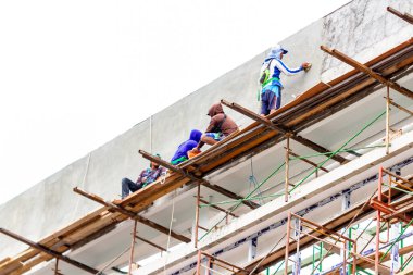 Simpang Lima Boyolali şehrinin çevresinde yüksek katlı bir bina inşaatında çalışan birçok erkek işçi yeterli güvenlik ekipmanı kullanmadan çalışıyor. BOYOLALI, İNDONEZYA - 18 Ekim 2021.