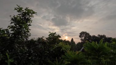 Güneş doğarken beyaz bulutların bir yerleşim yerinin çatısından görünüşü, güneşin tropik bölgelerdeki hareketi...