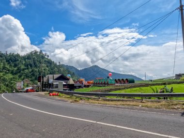 Dağlık bölgelerdeki doğal manzara serin hava, açık ve güneşli gökyüzü sakin yol koşulları ve yeşil bitkiler temiz hava sağlıyor.