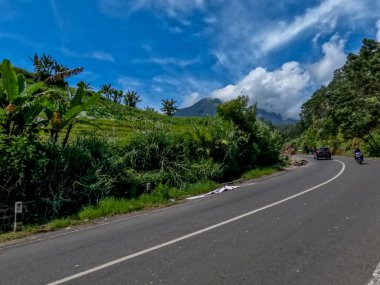 Dağlık bölgelerdeki doğal manzara serin hava, açık ve güneşli gökyüzü sakin yol koşulları ve yeşil bitkiler temiz hava sağlıyor.