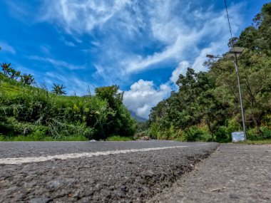 Dağlık bölgelerdeki doğal manzara serin hava, açık ve güneşli gökyüzü sakin yol koşulları ve yeşil bitkiler temiz hava sağlıyor.