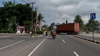 Magelang, Indonesia - August 30, 2022. A truck carrying containers is crossing the Yogyakarta-Magelang road, changing direction from heading to Yogyakarta back to Magelang