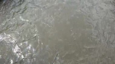 The surface of the water flow in an irrigation channel in the middle of the farmland, the water is slightly brown carrying mud and sand
