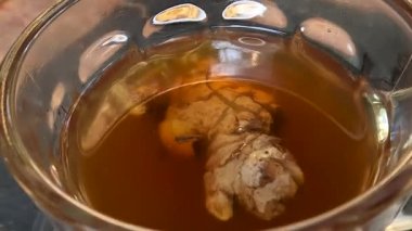 Tea and ginger infusion in a transparent glass cup, are herbal drinks that warm the body and increase immunity