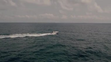 boat cuts through the sea mountains in the background