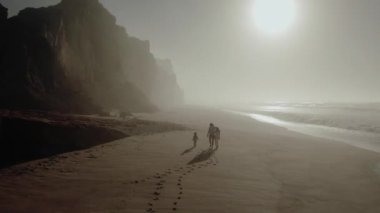 a married couple with a child is driving along the seashore footprints in the sand