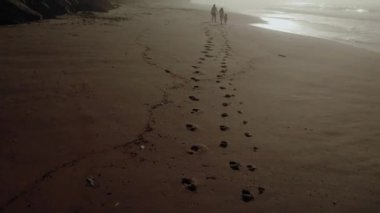 a married couple with a child is driving along the seashore footprints in the sand