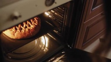 Böğürtlenli turta fırında pişiyor. Meyveli turtayı fırından çıkar.