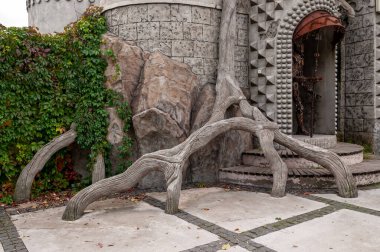 Duvarın yanındaki taş ağaç ve yapraklı demir çit.