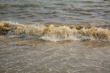 Güneşli sahilde kara deniz dalgaları