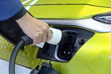 Şarj edilebilir şarj makinesini beyaz elektrikli araba prizine takan adamın eli elektrik enerjisi akıllı araçlar ve eko enerjisi için alternatif bir yakıttır.