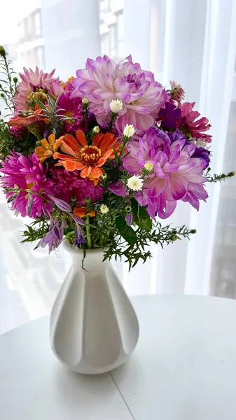 Beyaz vazodaki kır çiçekleri. Beyaz bir masadaki vazoda bir buket çiçek.