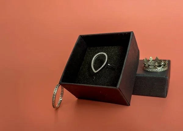 Kara bir kutuda, hassas bir arkaplanda Pandora tarzında bir düşüş şeklinde halka.