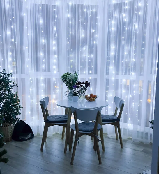 Panoramik pencerede çelenk. Işıkta İskandinav apartmanı