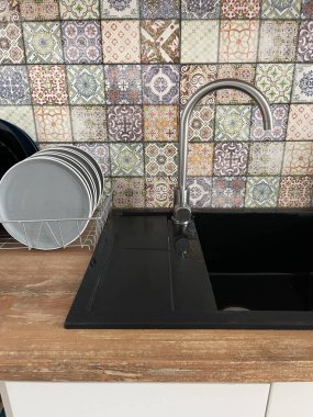 Mutfağın iç kısımlarına yakın çekim. Çok renkli duvar, yamalı döşemeler. Siyah kabuk. Modern İskandinav tasarımı. Ev dekorasyonu, temizlik konsepti.