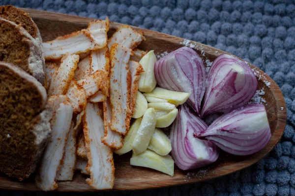 Fresh tasty lard with chopped onion and garlic on a wooden plate
