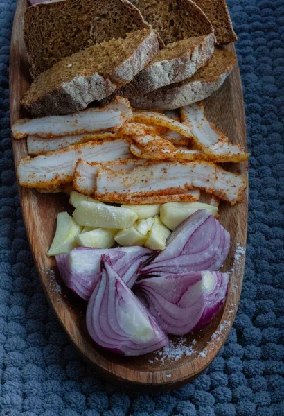 Fresh tasty lard with chopped onion and garlic and black national Ukrainian bread on a wooden plate