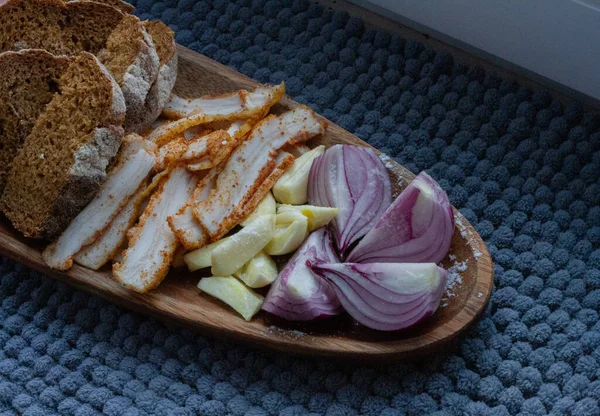 Fresh tasty lard with chopped onion and garlic on a wooden plate