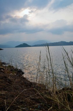 Göl manzarası, nehir kıyısı ve dağlar. Güzel göl kıyısı ve gün batımının yansıması bir göl üzerinde