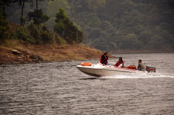 Shillong, Hindistan - 09 Aralık 2012: İnsanlar kış mevsiminde dağların ve ağaçların güzel doğasına karşı gölde sörf yapmaktan keyif alıyorlar.