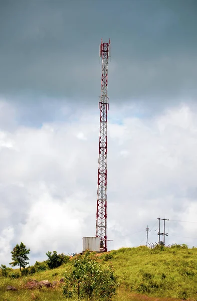 Telecommunication antenna or cell tower on a mountain. A view of a high cell tower on a hillock in a dark cloudy sky in the background