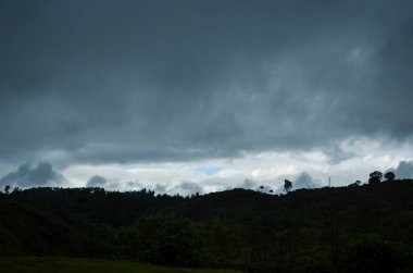 Dağların silueti ve akşamları karanlık bulutlu gökyüzü. Gün batımında sağanak yağmur zamanı