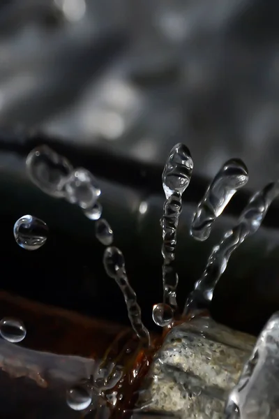 Closeup of an iron water pipe and water splashing from the pipe. Freeze motion of water leaking from the water pipe in the city