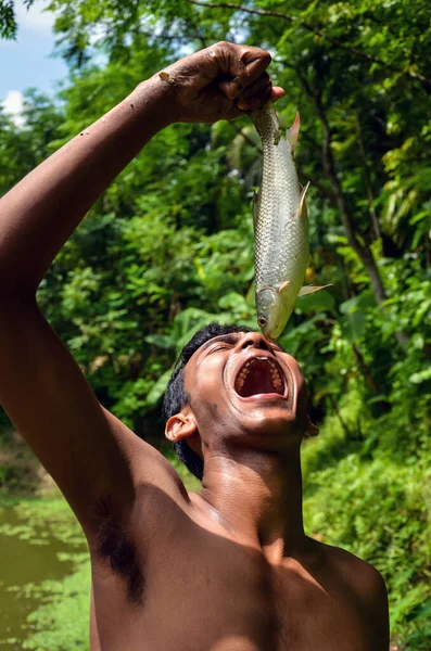 2012年7月23日 孟加拉国帕布纳 一名亚洲男子举着一条鱼 试图吃生鱼片 小男孩在池塘里吃生鱼片 — 图库照片