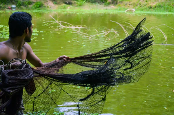 一名年轻的亚洲男子用通常被称为池塘中的捕鱼网的纤维制成的渔网捕鱼 男人把渔网扔进水里 以便从池塘里捕鱼 — 图库照片