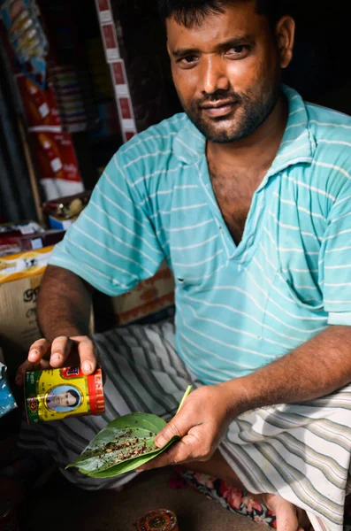 Pabna, Bangladeş - 23 Temmuz 2012: Müşterilere betel yaprağı satan küçük bir girişimci. Küçük işadamı Asya 'da çok popüler olan betel yaprağına tütün eklemekle meşgul ve bu maddeye talep var..