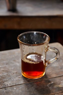 Closeup of a tea cup and half tea liquid inside. Glass cup and black tea on the table textured.