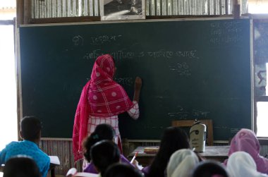 Gowainghat, Bangladeş - Kasım 06, 2019: Kırsal ya da uzak okullardan gelen öğretmen öğrencilere matematik öğreterek öğrencilerin denklemlerini kara tahtaya yazarak.