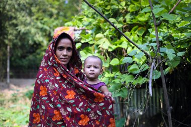 Gowainghat, Bangladeş - 06 Kasım 2019: Sağlıklı bir anne ve sağlıklı bir bebek, çocukların besleyici gıdaları için çiftlik bahçesine sebze ektikleri evin önünde duruyor.