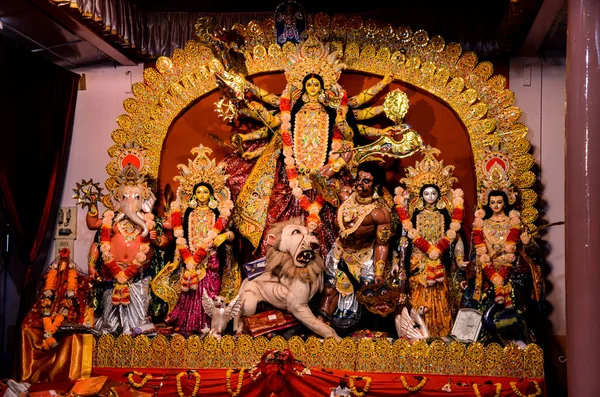 Ana Tanrıça Devi, iyinin kötülüğe karşı yay ve oklarla gücü, deniz kabuğu, kılıç, kalkan ve çan Durga puja veya Durga ashtami 'de aslanın başında oturuyor..