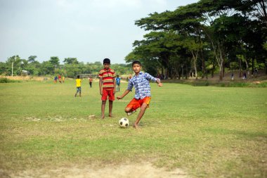 Gowainghat, Bangladeş - Kasım 06, 2019: Çocuklar sahada futbol oynuyor. Genç bir erkek ya da çocuk topa vuruyor ve bir çocuk daha vurmaya hazır..