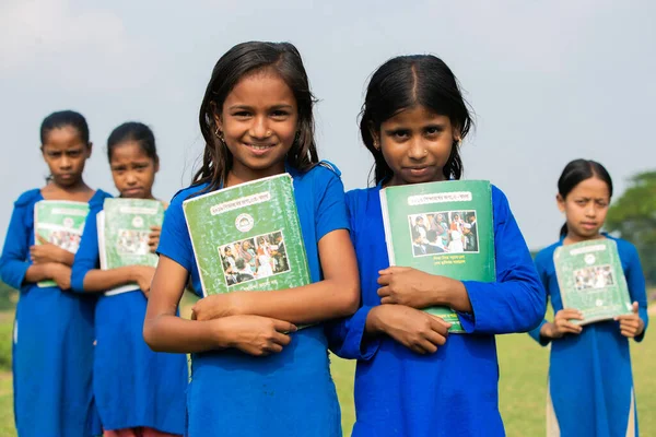 Gowainghat, Bangladeş - 06 Kasım 2019: Bir grup öğrenci kitaplarını sandığın önünde tutuyorlar. Okula giden kızlar kitaplarını aldıkları için mutlular. Okul elbiseli güzel kızlar kitapları tutuyor..