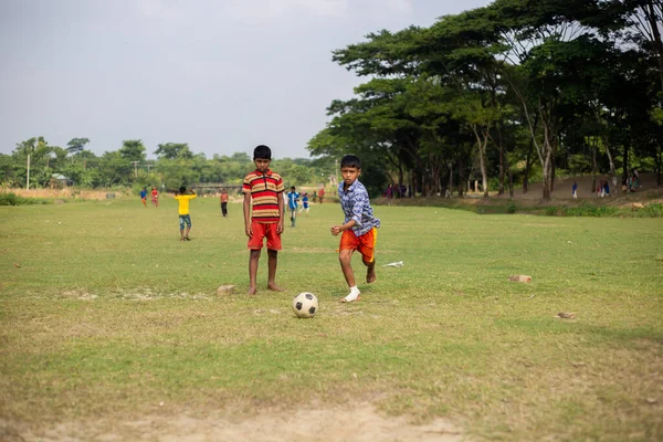 Gowainghat, Bangladeş - 06 Kasım 2019: Genç bir çocuk antrenman maçında topa yerden vurmak için koşuyor. Çocuklar futbol oynuyor. Futbolcu gol için futbol oynuyor..