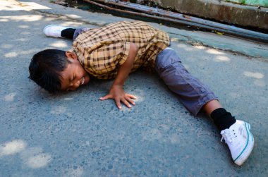 Shillong, Hindistan - 20 Ekim 2012: Küçük çocuk sokakta dans hareketleri uyguluyor. Yolda yoga yapan bir çocuk. Küçük çocuk yolda bacakları esnetiyor ve kafaya dokunuyor. Dans gösterisinde tehlikeli bir hamle.