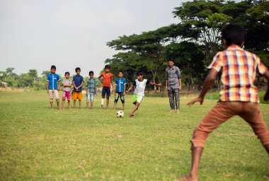 Gowainghat, Bangladeş - 06 Kasım 2019: Futbola penaltı atışı olarak hazır çocuk. Küçük çocuklar ya da çocuklar sahada futbol antrenmanı yapıyorlar ve koç onlara nasıl futbol oynanacağını gösteriyor..
