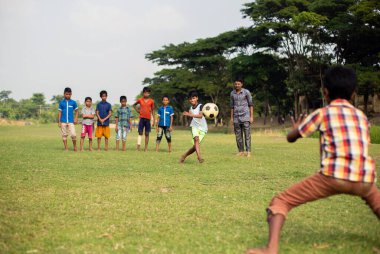 Gowainghat, Bangladeş - Kasım 06, 2019: Bir erkek çocuk tarafından gol için atılan uçan futbola seçici odaklanma. Kaleci bir futbol maçı ya da futbol maçında yüzen topu savunma olarak yakalamaya hazır..