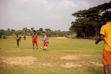 Gowainghat, Bangladeş - 06 Kasım 2019: Genç çocuk penaltı atışı için topa vuruyor. Çocuklar yeşil alanda futbol oynayıp pratik yapıyorlar..
