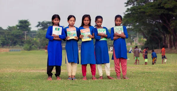Gowainghat, Bangladeş - 06 Kasım 2019: Kırsal eğitim için ücretsiz kitaplarını almaktan mutluluk duyan bir grup öğrenci. Göğüsleri kitaplarla dolu okul üniforması giyen kızlar..