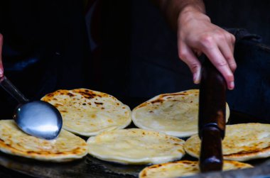 Adam kızarmış yağda roti pişiriyor. Parathas büyük bir tabakta pişiriliyor.