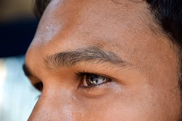 Selective focus on the young man eyes, eyebrows and nose. Extreme closeup of the eyes of a man looking outside