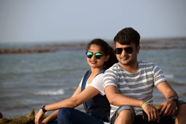 Deniz kıyısındaki mercanda oturan mutlu genç çift balayının tadını çıkarıyor. Romantik zaman geçip gidiyor sevgililer yan yana oturuyor