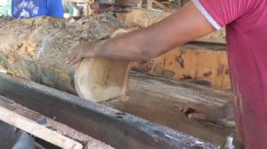 Pabna, Bangladesh - August 08, 2022:Pabna, Bangladesh  August 08, 2022: Men cutting a big tree with a modern saw machine in a wood sawmill. Daily workers or laborers slicing tree wood with automatic wood cutting machines set on a table
