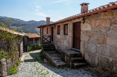 Portekiz 'in Assiento kasabasında, taştan dağların, mavi gökyüzünün ve yeşil çalıların arka planında taştan bir yolu olan eski bir ev.