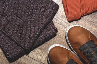 Ahşap arka planda turuncu şapkalı ve kahverengi eşarplı botlar.