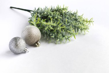 Noel konsepti arka planında, iki farklı gümüş renkli, parlak noel topu, beyaz üzerine yeşil dal, yazı için yer, yan görüş